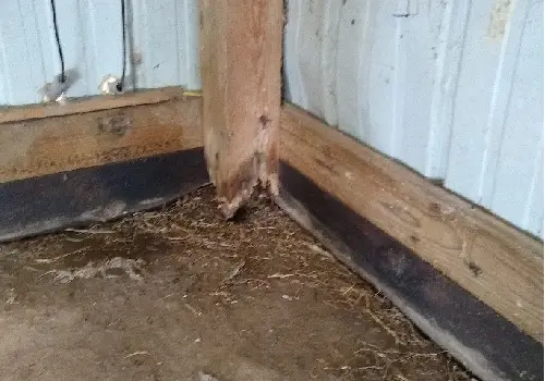 The corner of a post-frame structure with a rotted wood column