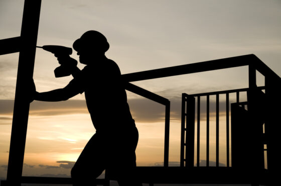 A construction worker uses a drill as he works on a building frame. Wisconsin Post-Frame Solutions for Contractors